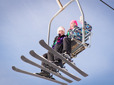 A skier and snowboarder enjoying their day at Snow Trails Ski Resort in Mansfield Ohio USA. They are using the ski lift to reach the top of the snowy slope. A classic winter sports scene.