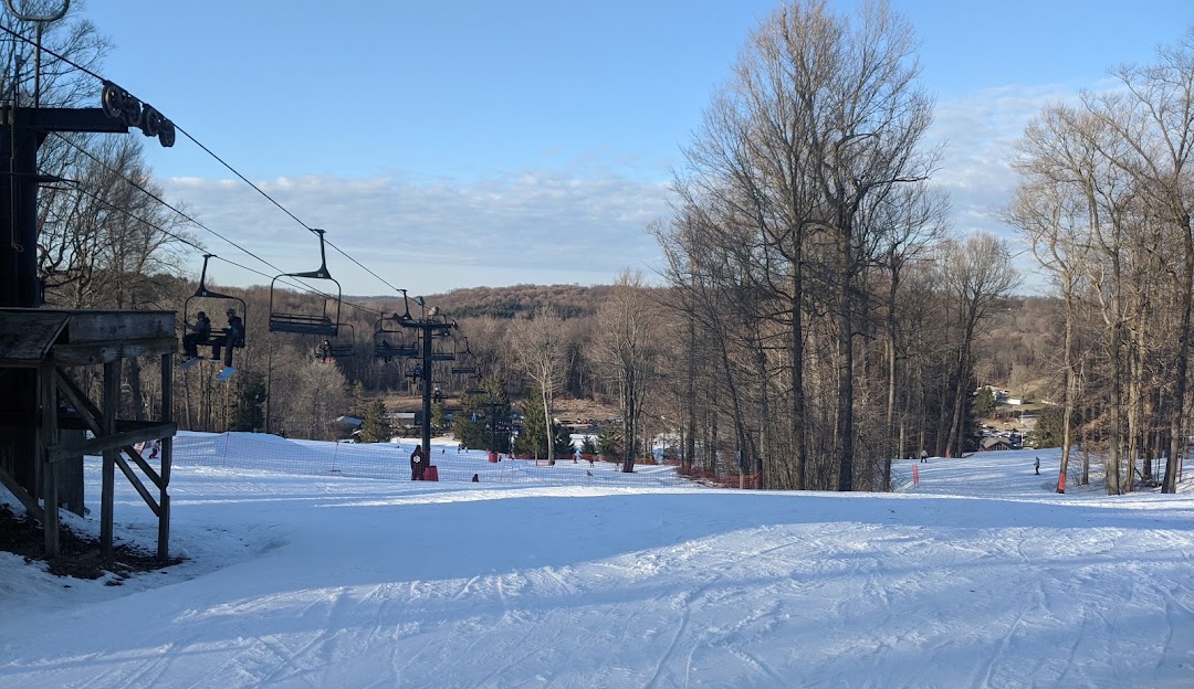 A winter scene at Snow Trails ski resort in Mansfield Ohio showcasing skiers on slopes chairlifts carrying people and a charming chalet nestled amidst the snowy landscape.