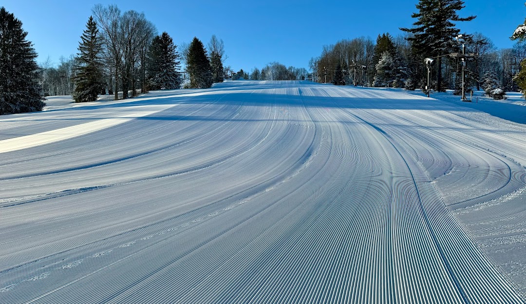 Snow-covered landscape showcasing a bustling winter sports scene at Snow Trails in Mansfield Ohio. Skiers and snowboards enjoy the slopes with a welcoming chalet in the background.