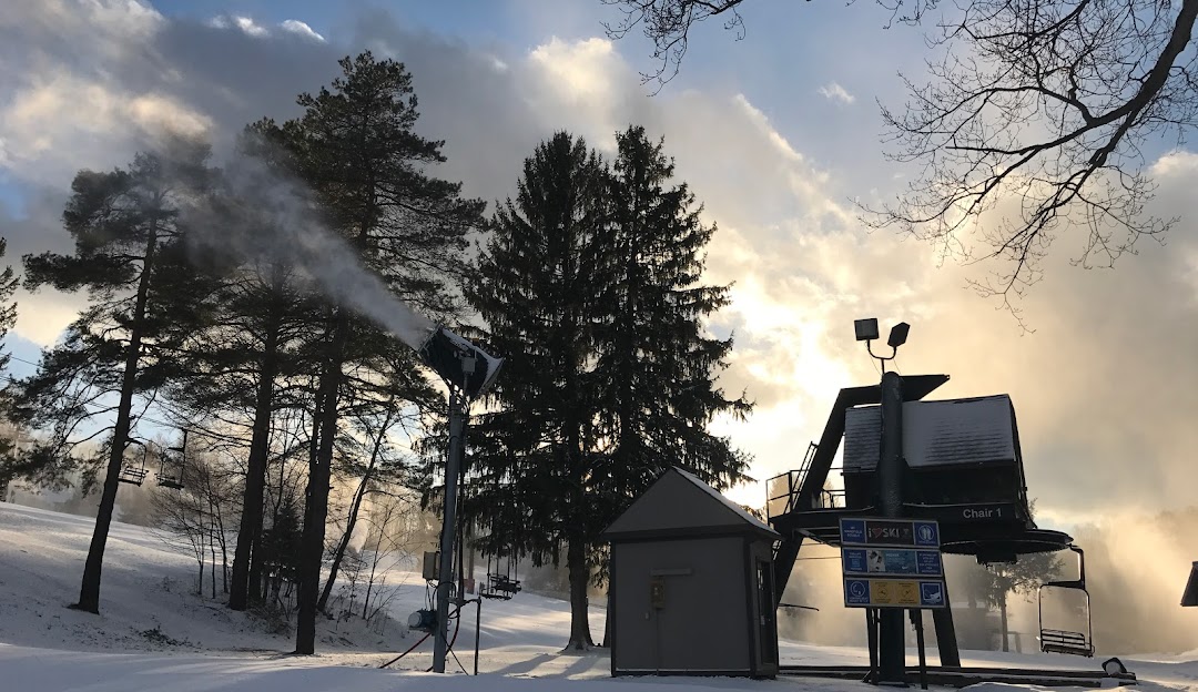 Winter sports enthusiasts enjoy a stunning snowy landscape at Snow Trails in Mansfield, Ohio. Skiers and snowboarders take to the slopes, illuminated by radiant sunlight while a ski lift patiently waits nearby.