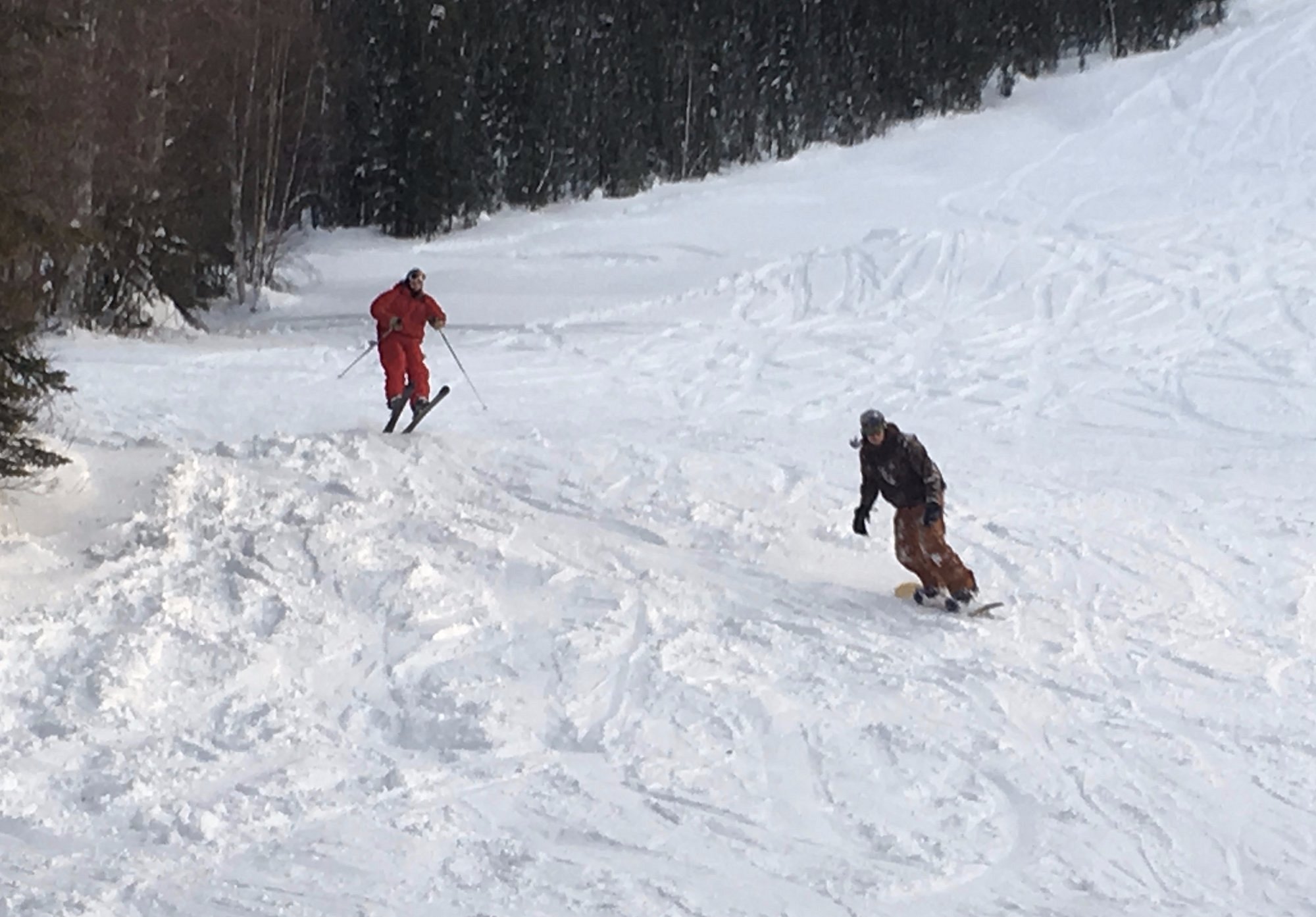 A skier descending Moose Mountain in Fairbanks, Alaska, with a ski resort and challet in sight. The scene encapsulates winter sports, with a possibility of a family skiing nearby.