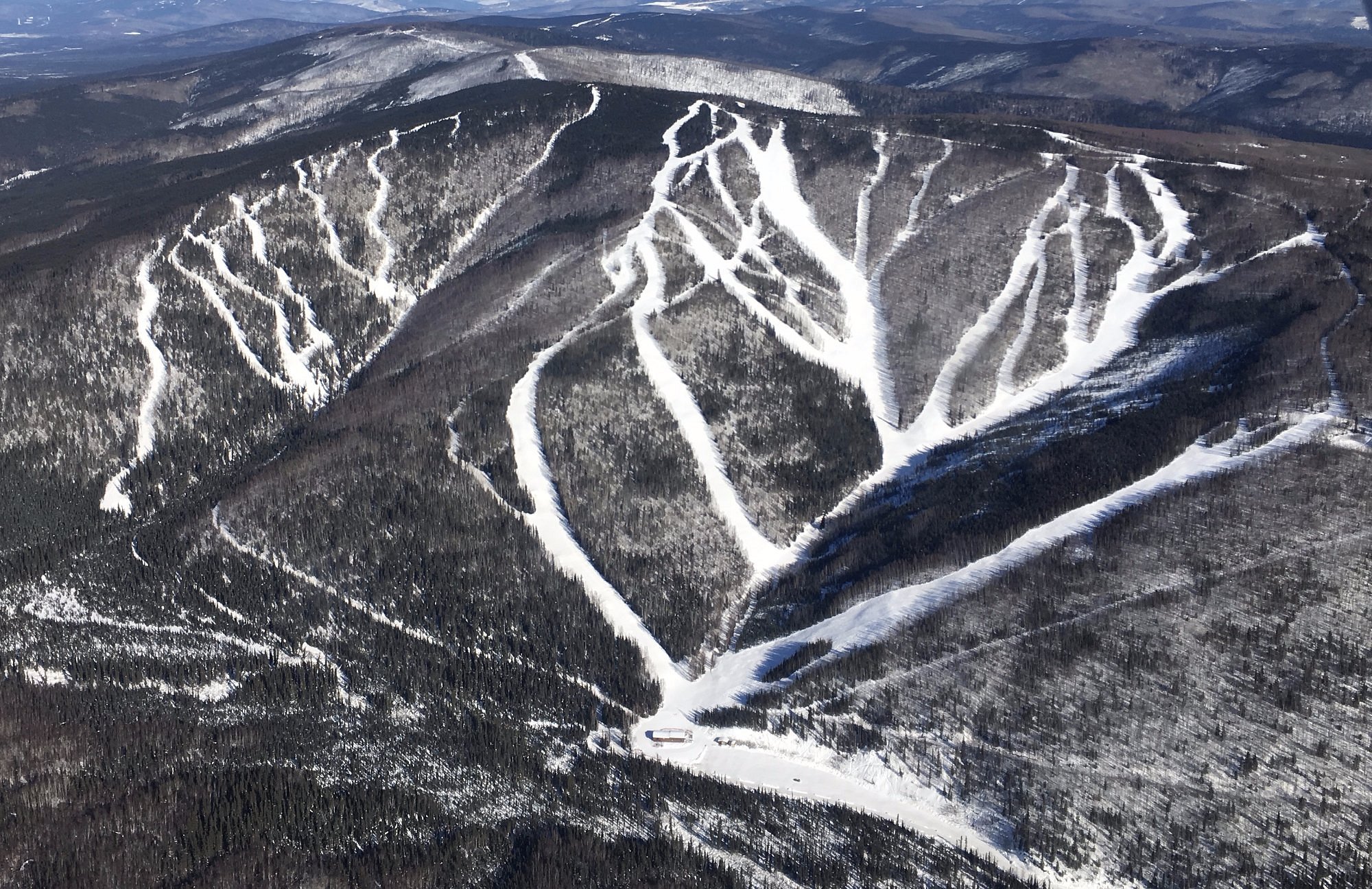 A skier enjoying the snow-covered slopes of Moose Mountain ski resort in Fairbanks Alaska. The winter sports scene showcases the stunning mountain backdrop.