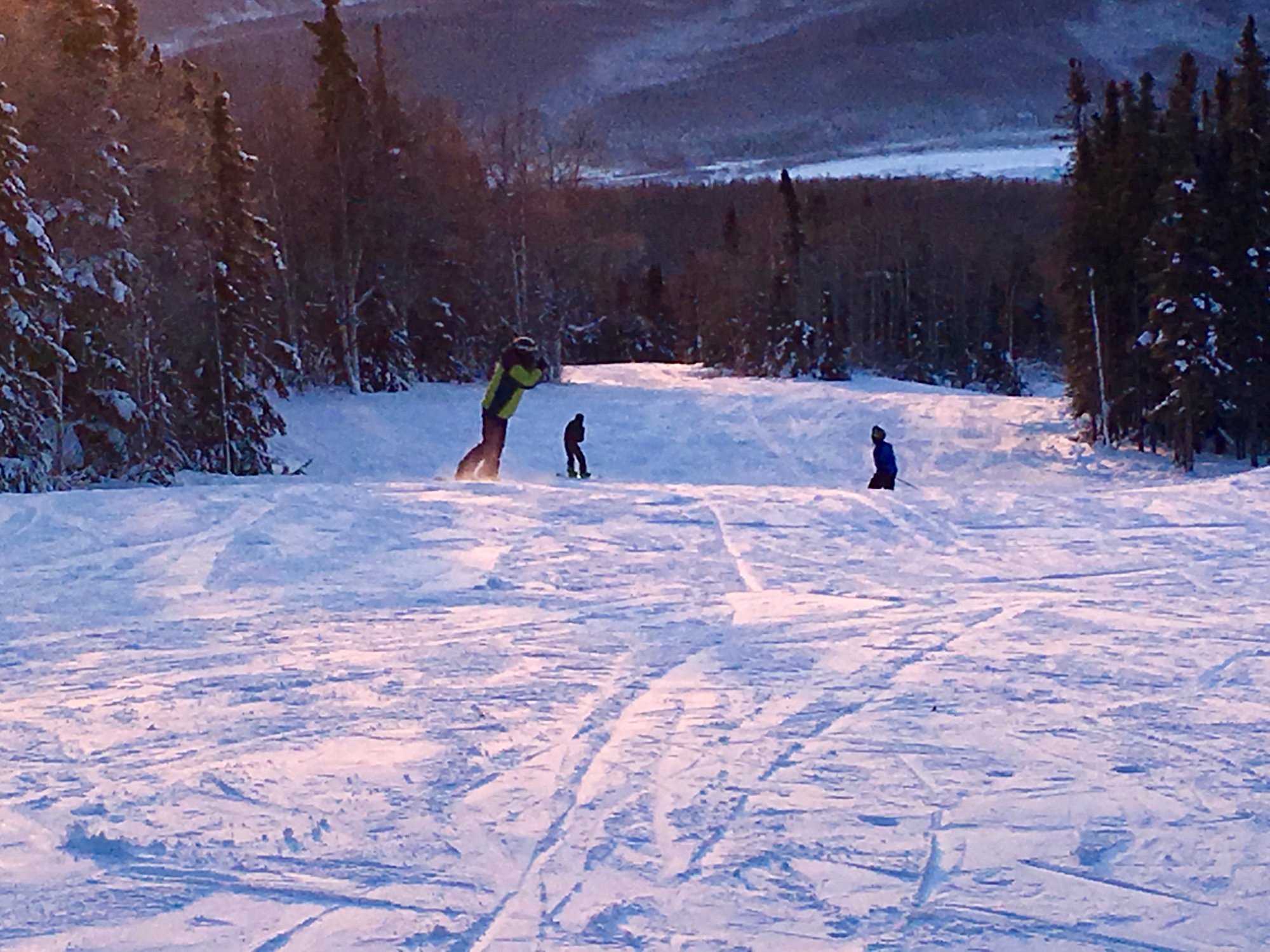 A winter sports scene on Moose Mountain in Fairbanks Alaska featuring a skier in action on the snow-covered slopes. Nearby a ski lift hints at a bustling ski resort.