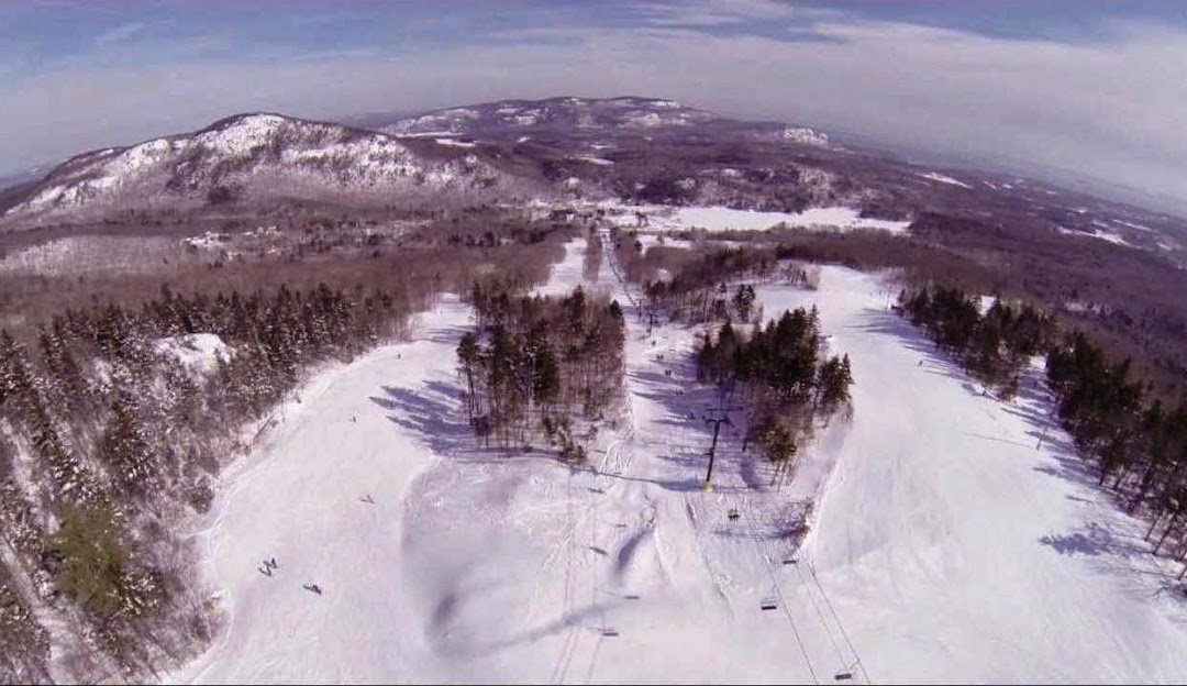 Skiers at the vibrant winter sports scene at Camden Snow Bowl in Maine, USA, traversing down the snow-covered slopes and boarding a ski lift.