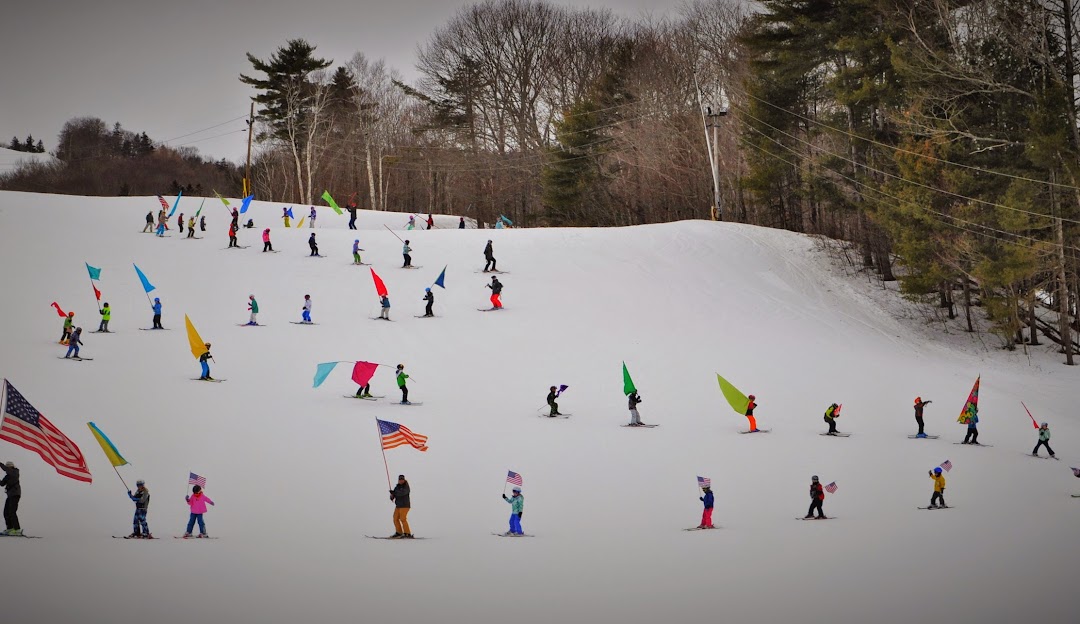Winter sports scene at Camden Snow Bowl, Maine, with numerous people enjoying skiing and snowboarding activities amidst the snowy landscape.