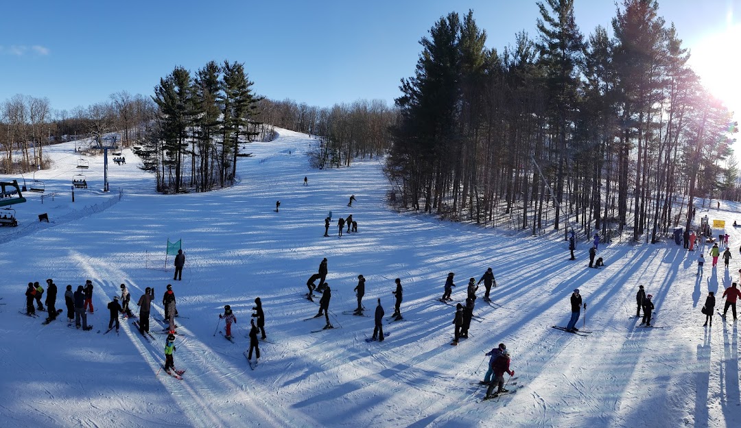 Winter sports scene at Boler Mountain in London, Ontario featuring a group of people skiing down the snowy slopes of the resort.