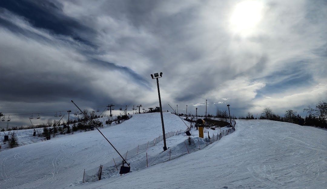 Winter scene at Boler Mountain, London, Ontario, Canada; featuring a ski lift, skiers and a ski resort, indicating a lively winter sports scene at a sports center.