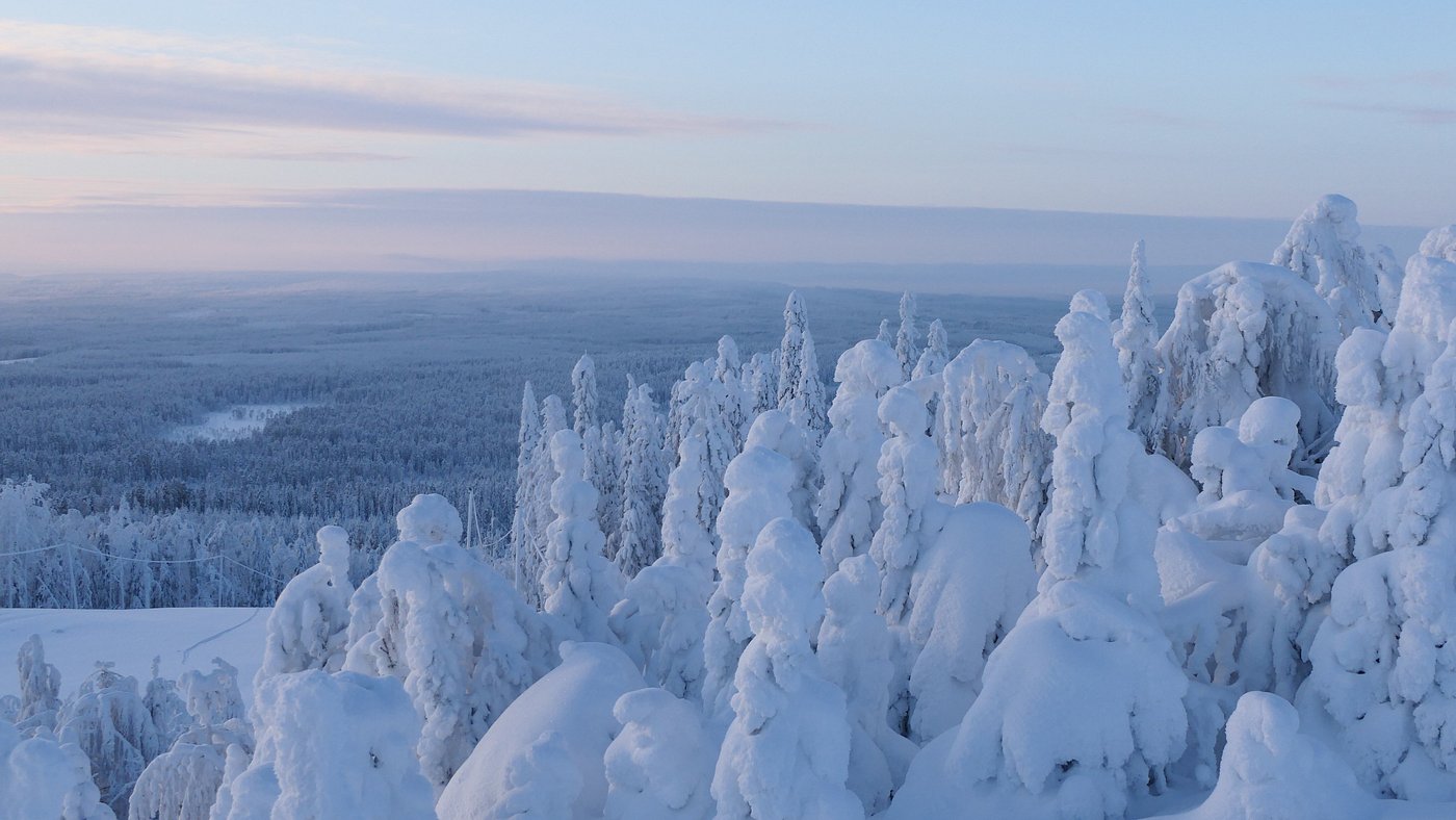 Winter scene in Ukkohalla, Finland featuring breathtaking snowy landscape, a mountain in the distance, and signs of winter sports activities.