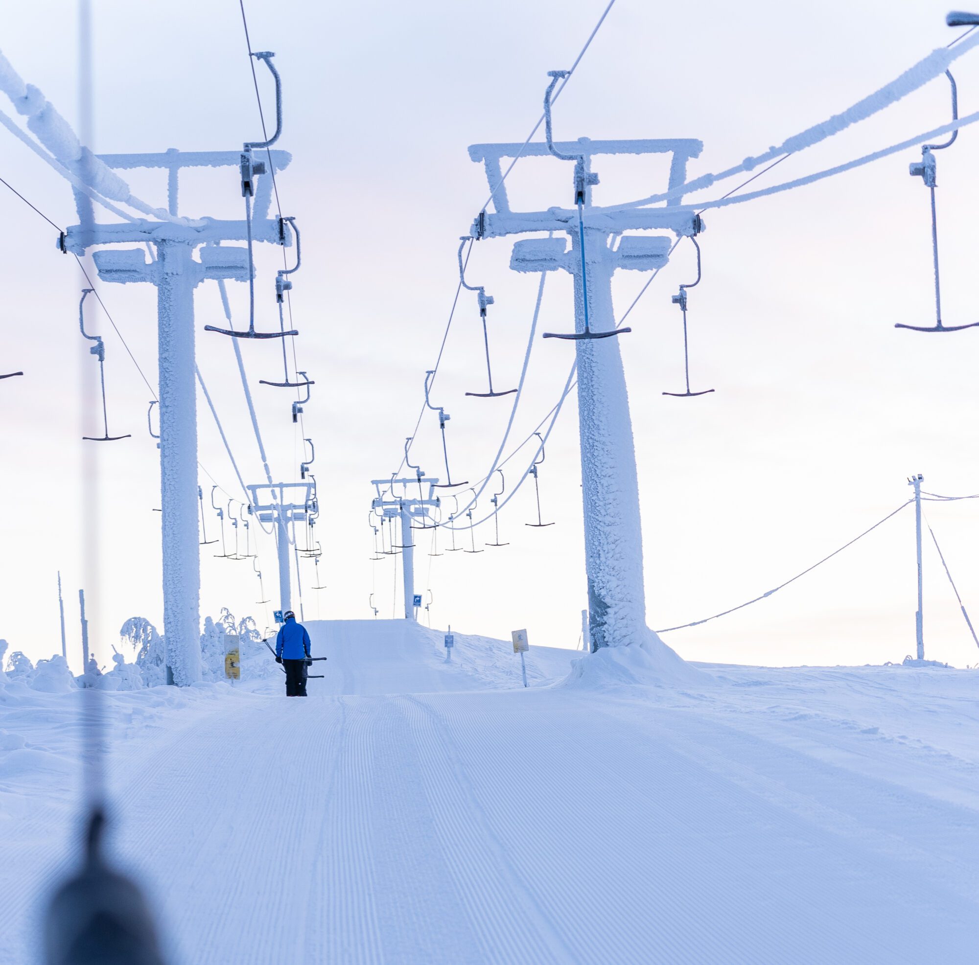 Winter sports scene at Ukkohalla, Kainuu, featuring a ski lift, a skier enjoying the slopes, and a stunning winter landscape in the backdrop of a ski resort.
