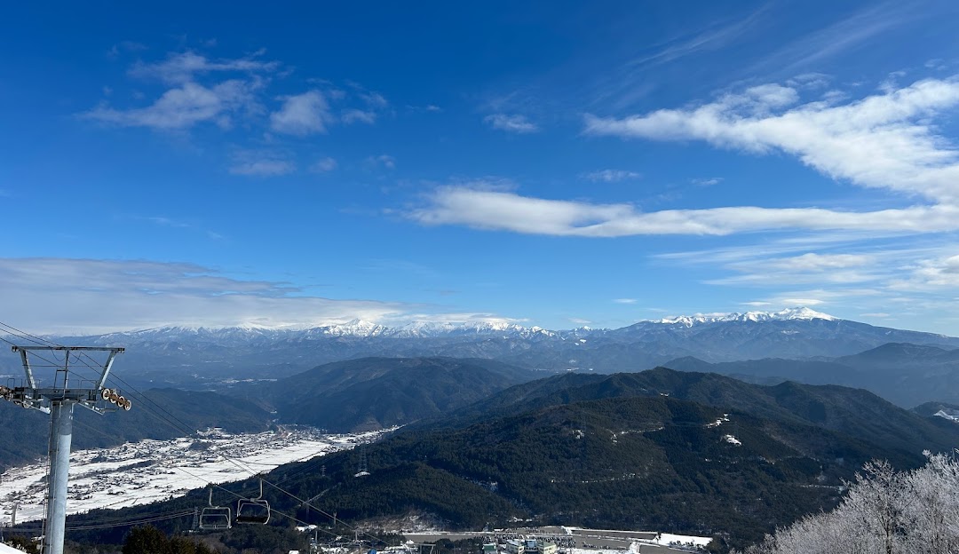 Ski resort scene at Mont Deus Hida-kuraiyama Snow Park, Japan, featuring a chalet surrounded by stunning winter scenery atop a snow-covered mountain.