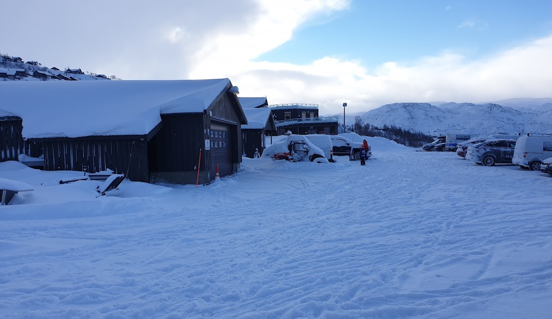 A scenic view of Haukelifjell Skisenter, a winter sports centre in Vågslid, Norway. The snowy slopes of this renowned ski resort are complemented by a charming chalet and a rustic mountain hut.
