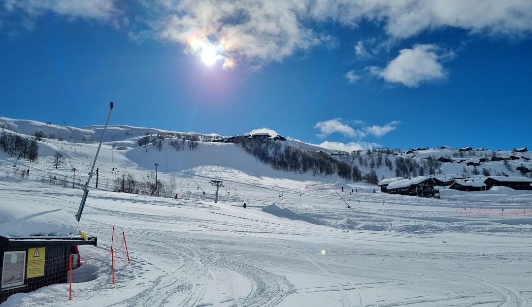 A scenic winter landscape at Haukelifjell Skisenter in Vågslid, Norway, featuring a ski resort, traditional chalet, and sports enthusiasts enjoying winter activities.