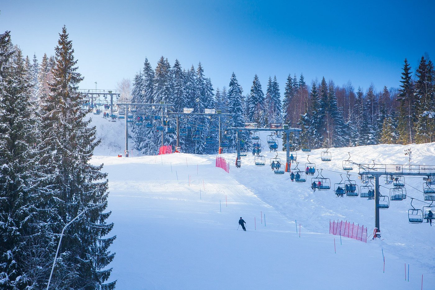 Winter sports scene at a ski resort in Sunne in Rottneros, Central Sweden, featuring a ski lift and a skier amidst the snowy slopes.