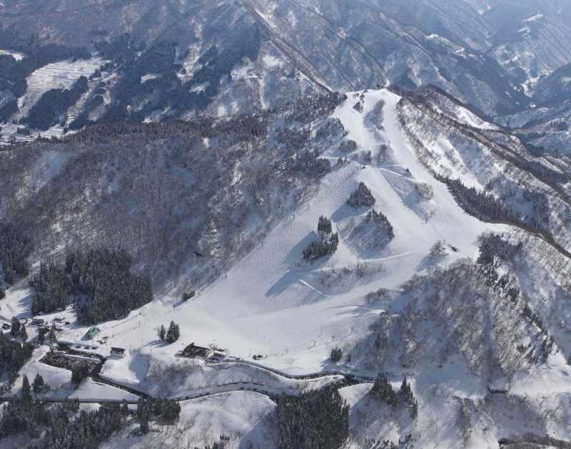 A snowy view of Taira ski resort in Nanto, Japan, highlighted by a cozy chalet nestled at the base of the mountain. The scene captures the thrill of winter sports on the snow-covered slopes.