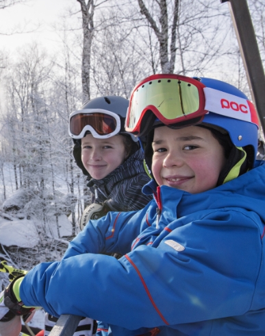 A winter sports scene at Mont Habitant in Quebec showcasing a skier and family enjoying skiing near a chalet in a winter sports centre.
