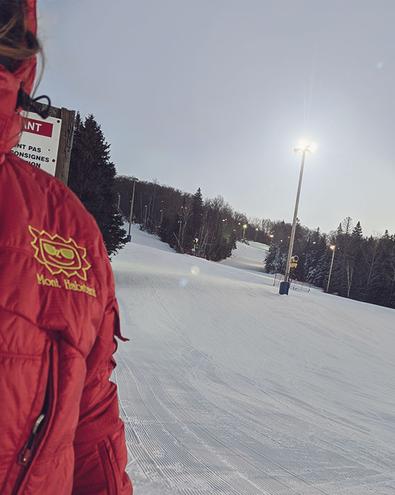 A skier and snowboarder enjoying winter sports at the Mont Habitant ski resort in Saint-Sauveur Quebec surrounded by beautiful snow-covered trees and slopes.