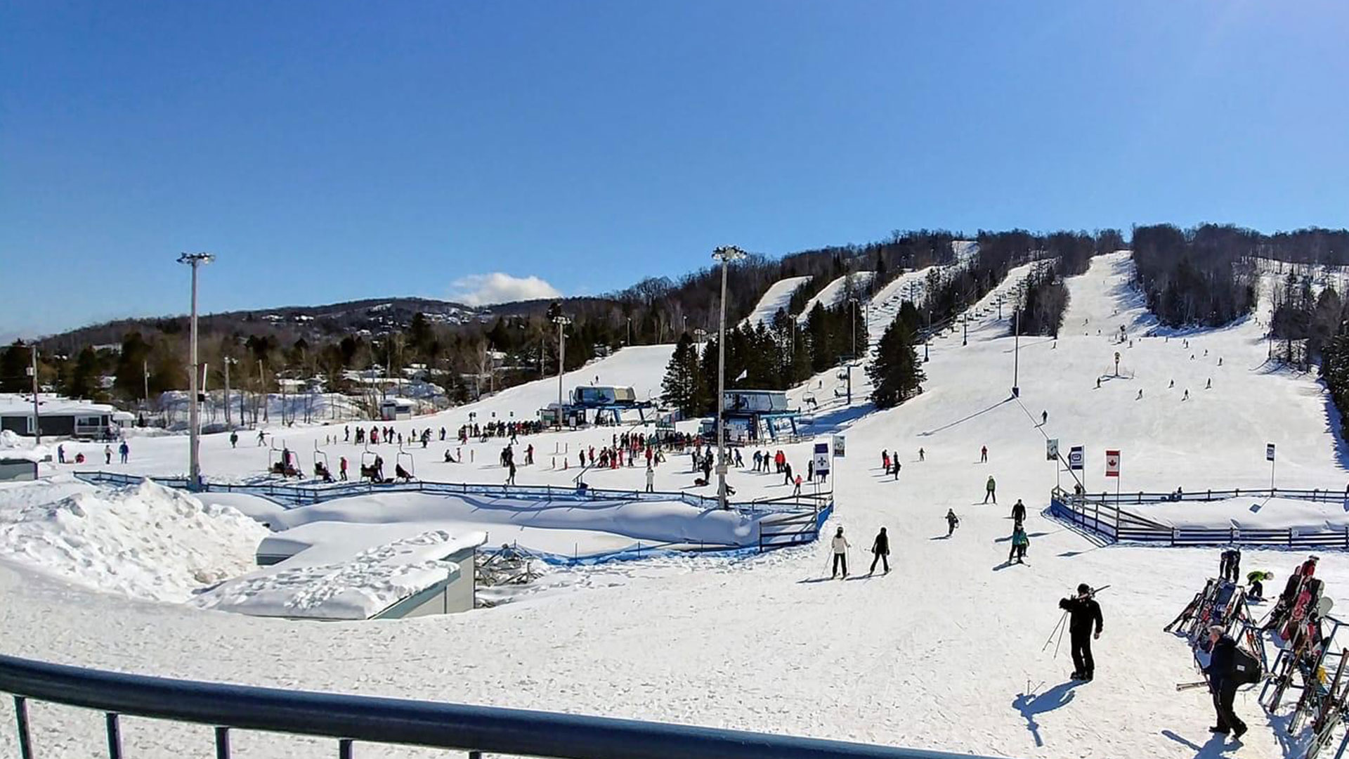 Winter sports enthusiasts enjoying their day at Mont Habitant, a ski resort in Saint-Sauveur, Quebec, with a ski lift visible in the scenic snow-covered landscape.