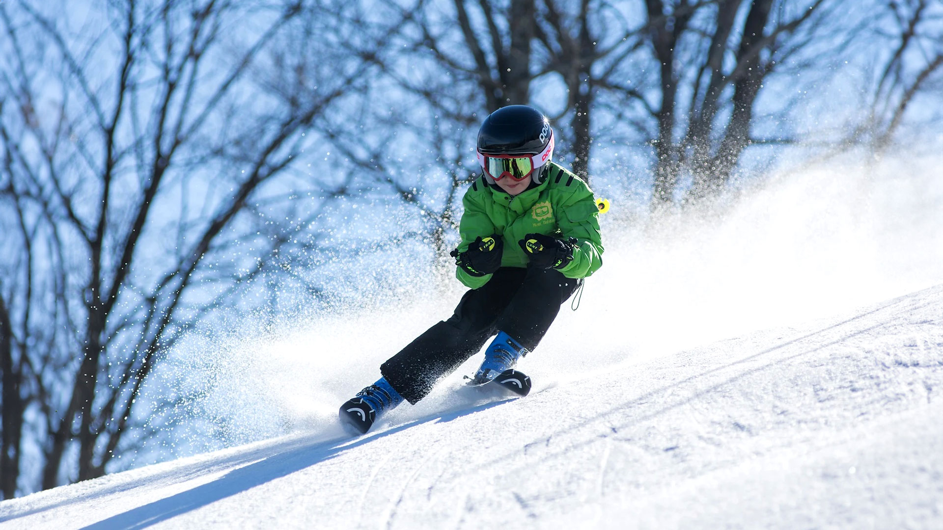 A skier and a snowboarder enjoying a sunny day on the snowy slopes of Mont Habitant, a popular ski resort in Saint-Sauveur, Quebec. A child can be seen learning to ski nearby.