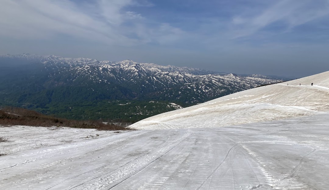 Winter sports scene at Gassan ski resort in Japan including a challet a mountain vista and snow-covered slopes.