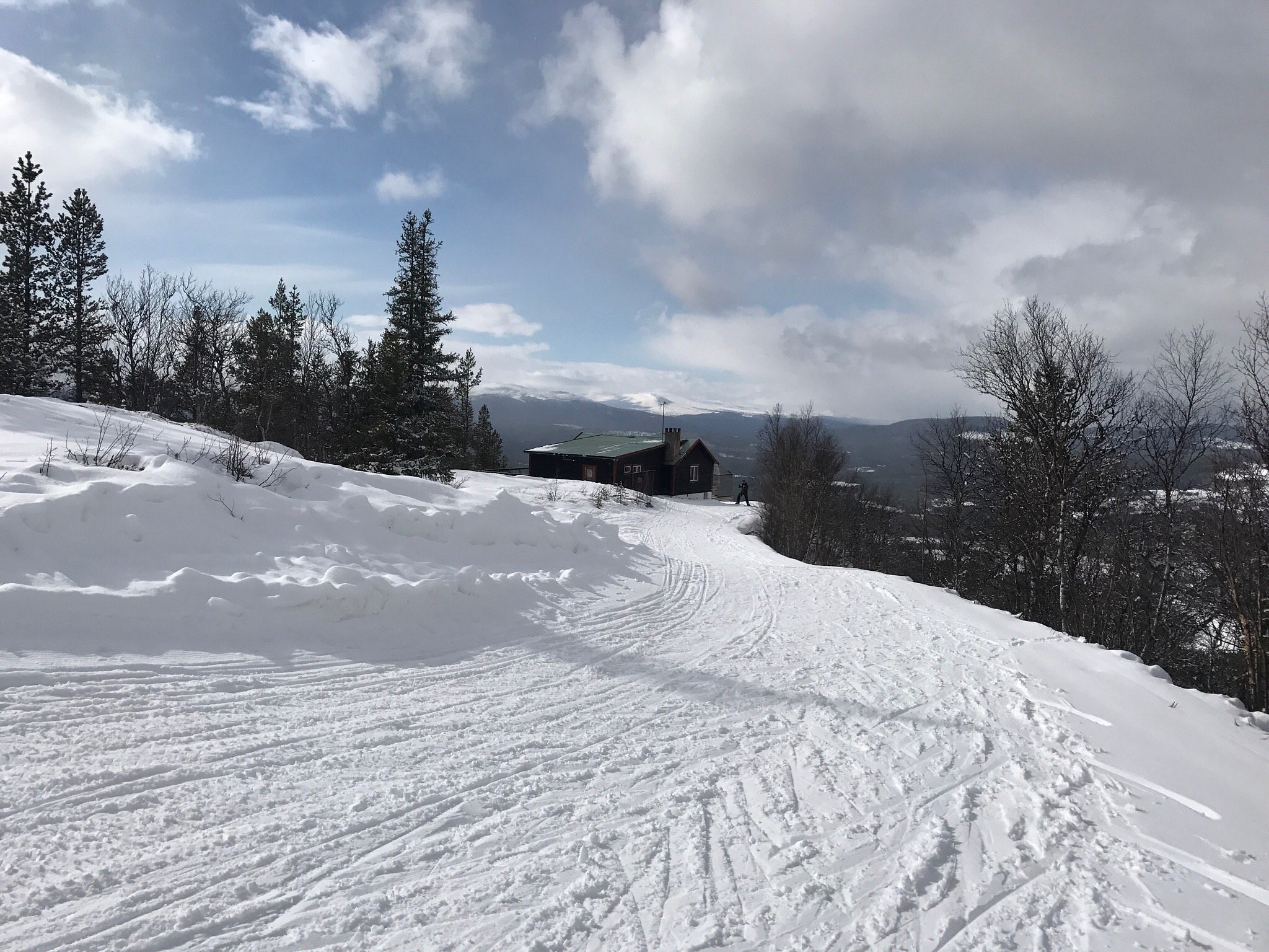 A skier navigating a snowy slope at Tännäskröket a winter sports scene in Northern Sweden. Visible elements include a ski resort ski lift and a snowmobile.