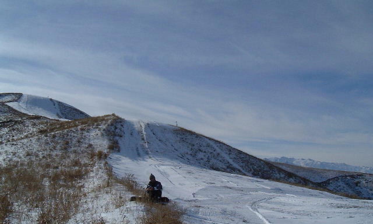 Orlovka in Kyrgyzstan - a person riding a snowmobile on a snowy slope.