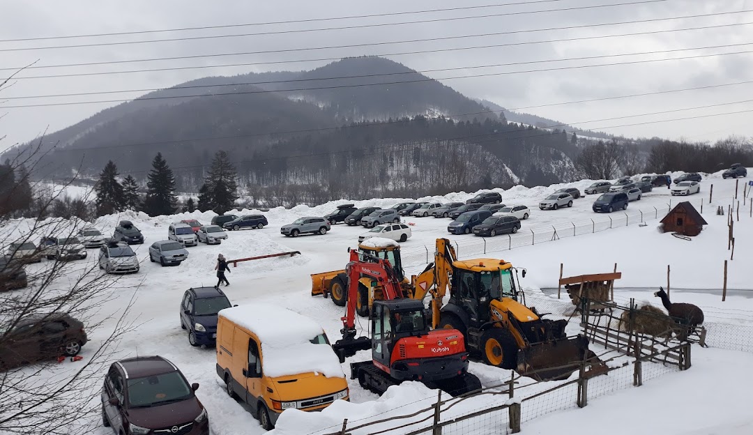 Winter scene at Ski Park Racibor in Oravský Podzámok, Slovakia showcasing numerous skiers navigating the slopes, with a ski lift and snowmobile visible in the background.