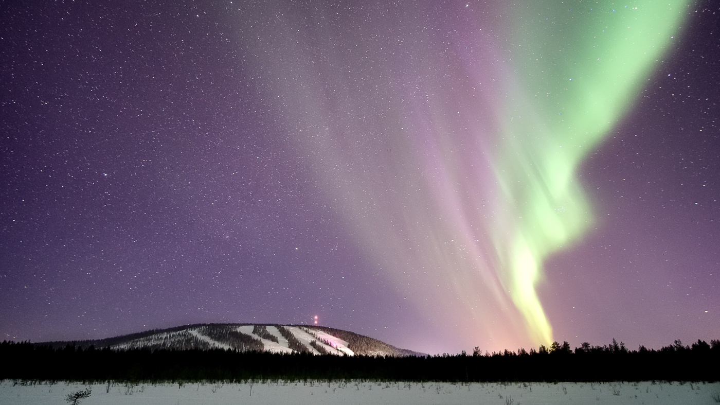 Winter view of Suomutunturi mountain in Lapland Finland featuring a picturesque snowy landscape a bustling ski resort and people enjoying winter sports activities.