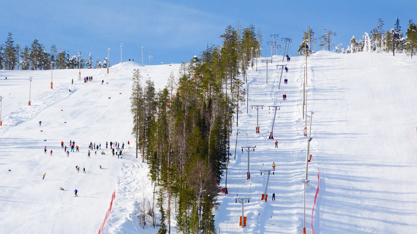 Winter sports enthusiasts enjoying a day at the Suomutunturi ski resort in Lapland, Northern Finland, with a ski lift visible amid snow-covered slopes.
