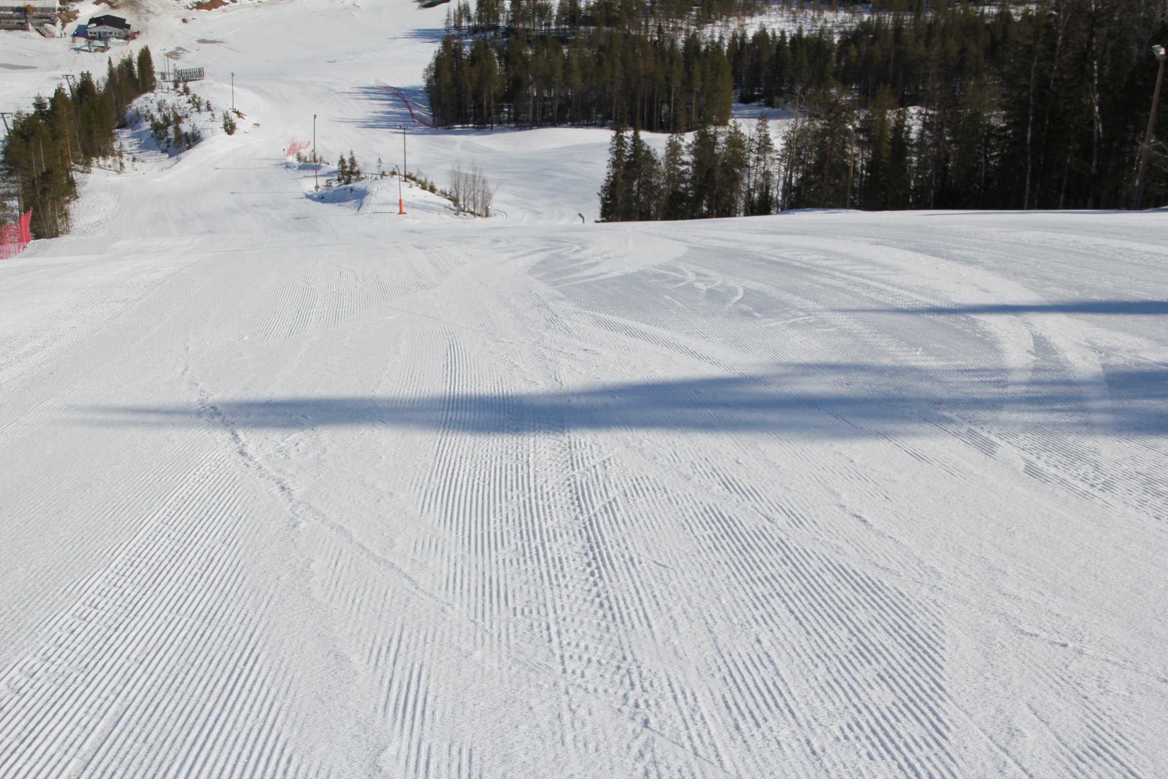 A skier swiftly glides down the snow-covered slopes at the Suomutunturi ski resort in Suomu Northern Finland accompanied by a ski lift in the background encapsulating a vibrant winter sports scene.