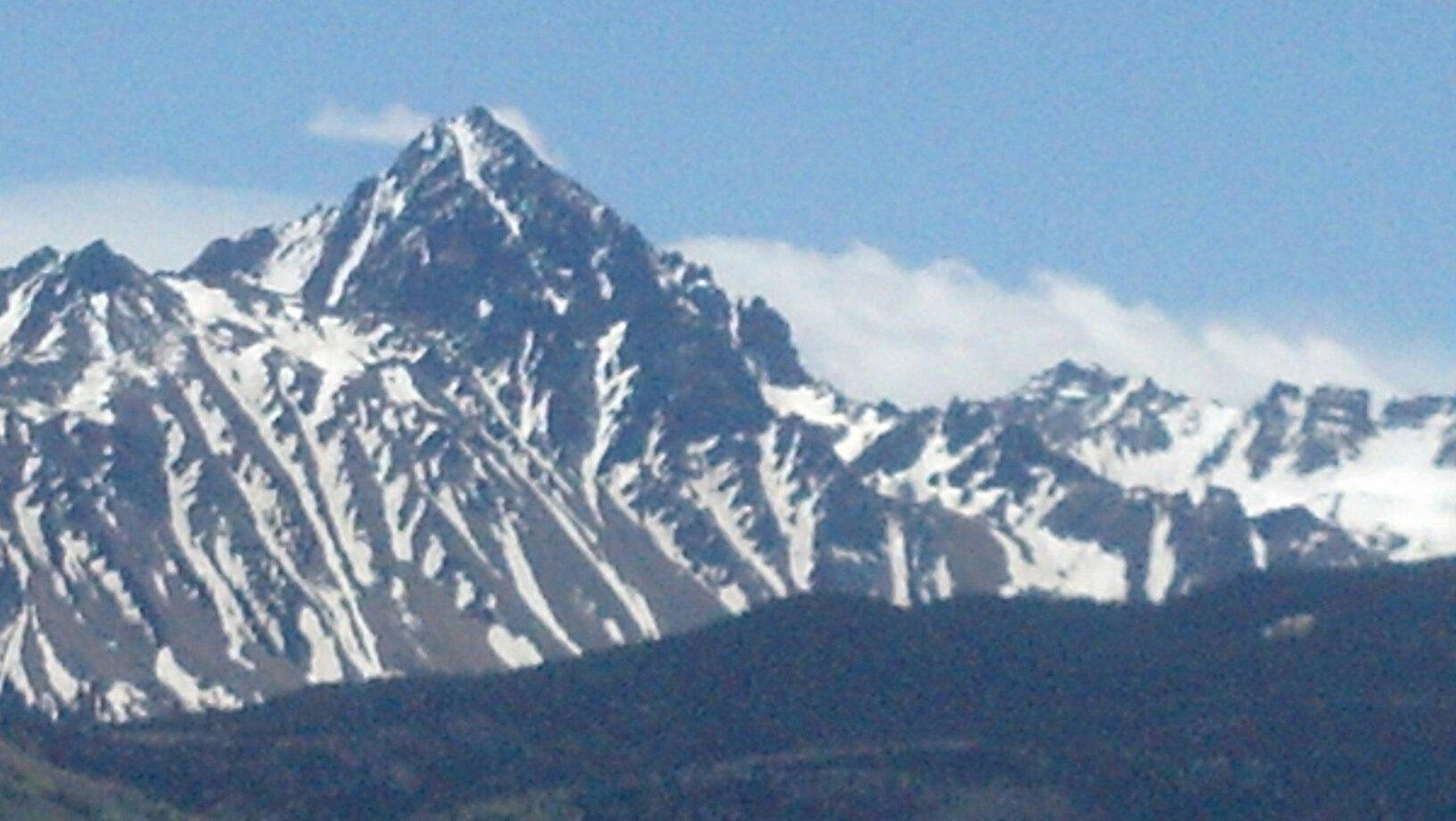 A mountain capped with snow visible in Alpine Valley, White Lake, Michigan. A chalet is nestled halfway up, and a lone skier can be seen descending the slope.