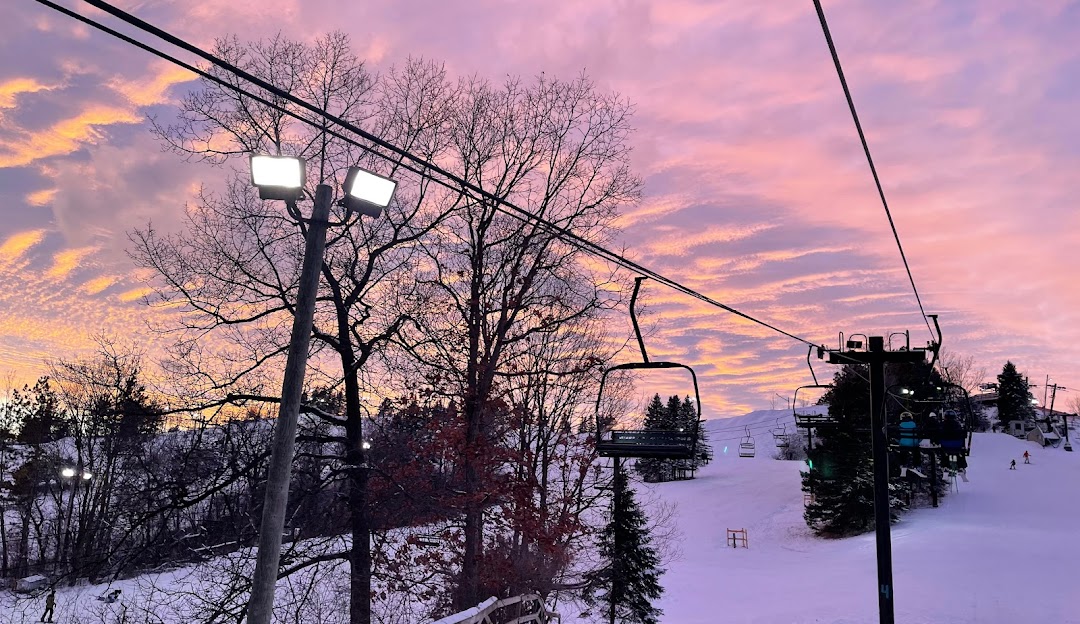 Winter sports enthusiasts enjoying a day out at Alpine Valley Ski Resort in White Lake, Michigan. A ski lift ascends amidst stunning winter scenery, providing a breathtaking view of the snowy landscape.