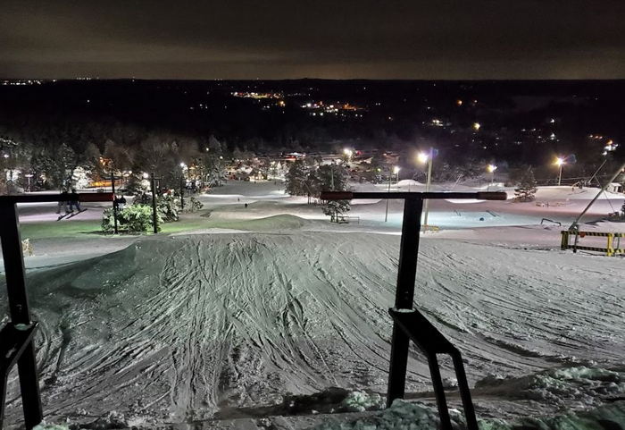 Winter sports enthusiasts enjoy a day at Alpine Valley Ski Resort in White Lake Michigan picturesque with snow-covered slopes a quaint chalet and a ski lift accessing the peak.