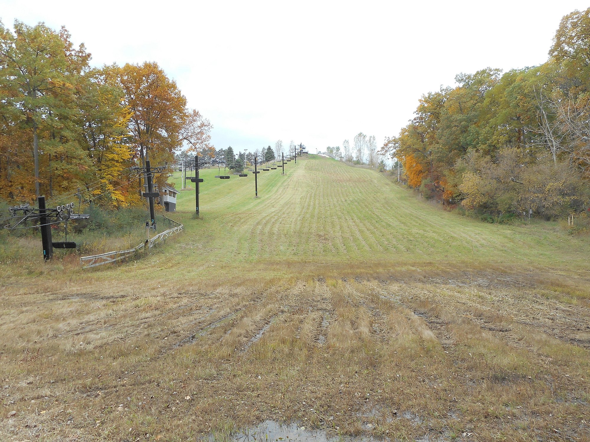 A picture of Alpine Valley in White Lake, Michigan featuring a charming challet. Winter sports enthusiasts can be spotted in the scene, with a ski lift in view. The picture vividly represents a bustling ski resort.
