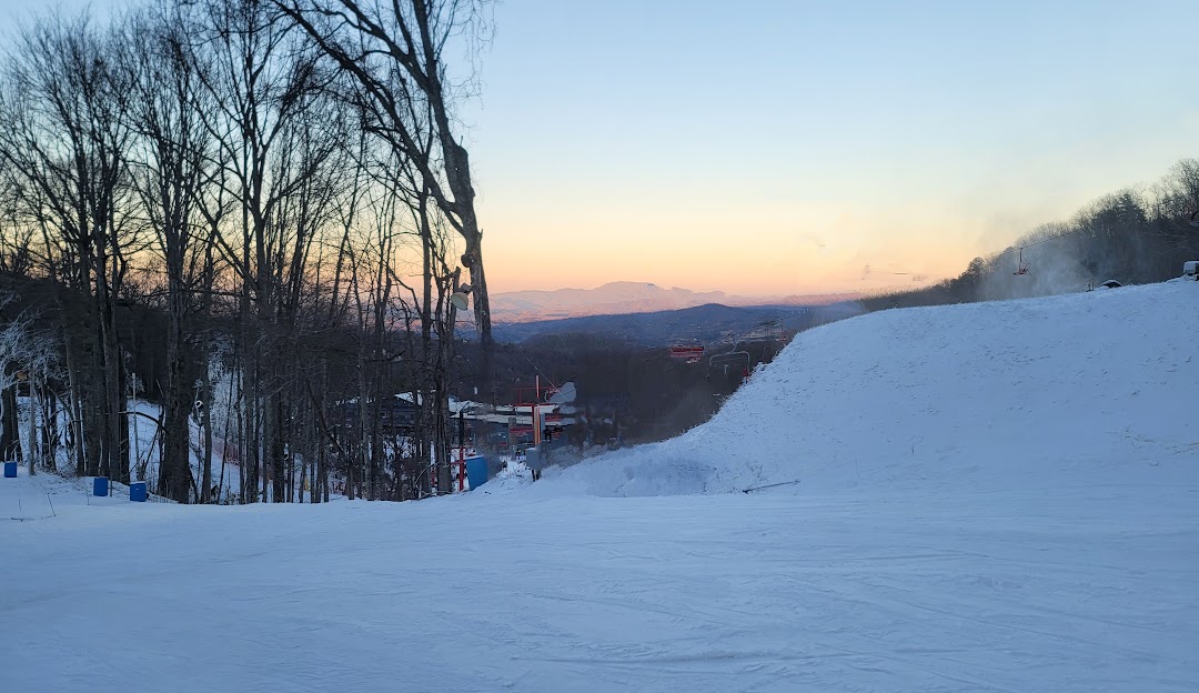 A vibrant winter sports scene at Ober Mountain ski resort in Gatlinburg Tennessee featuring a skier descending the snow-covered slopes with a ski lift visible in the background.