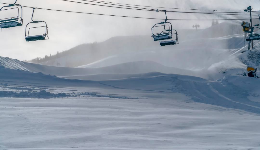 A ski lift ascending Ober Mountain at a ski resort in Gatlinburg, Tennessee. Skiers can be seen enjoying the snow-covered slopes in this vibrant winter sports scene.