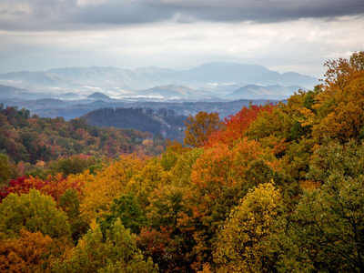 A picturesque winter scene at Ober Mountain Gatlinburg Tennessee showcasing a stunning mountain range adorned with lush forests. A charming chalet overlooks the snowy landscape where winter sports are taking place.