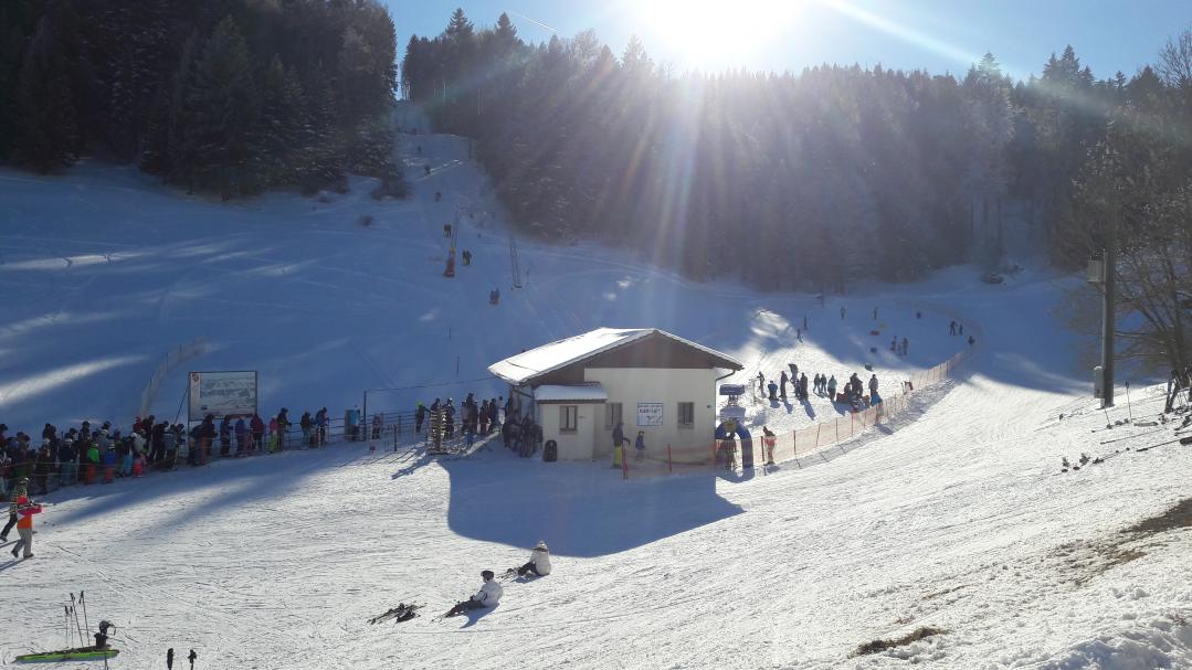 Winter sports enthusiasts enjoying at a sports centre in Tramelan, Switzerland, with a cosy chalet nearby and striking winter scenery at a ski resort.