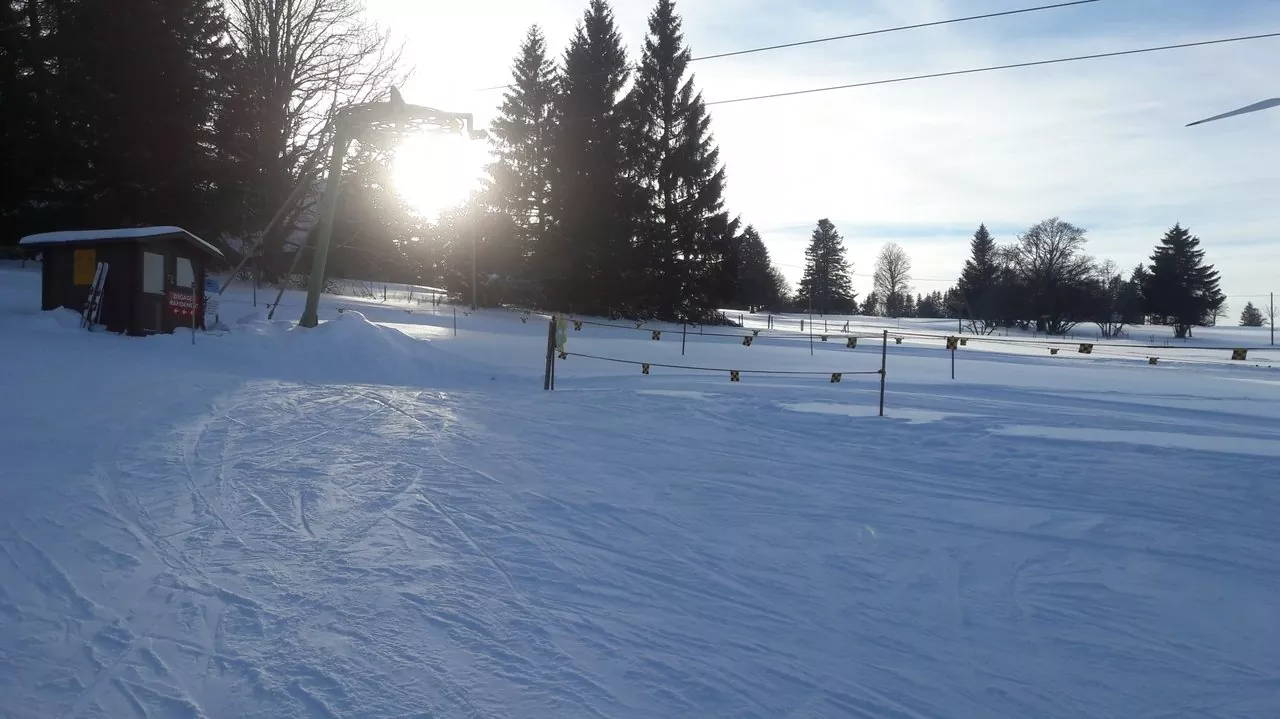 Winter sports scene at Tramelan, Bernese Jura, Switzerland, featuring a bustling winter sports centre, charming chalet, and stunning snow-covered scenery.