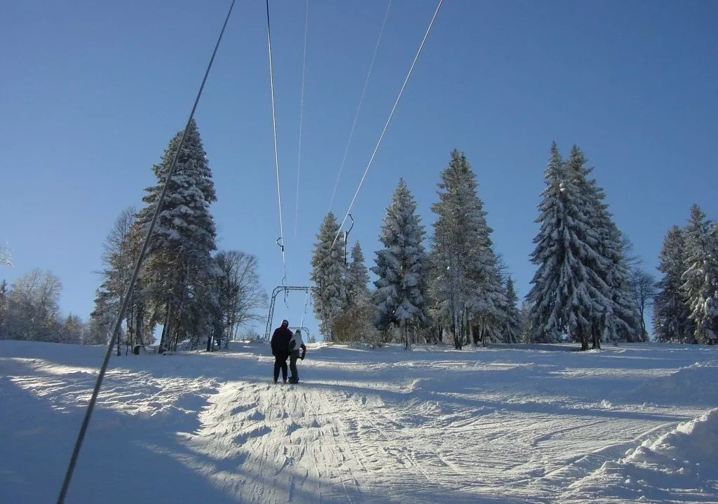 A ski lift at the Tramelan ski resort in Bernese Jura, Switzerland. This winter sports scene also features a skier enjoying the slopes.