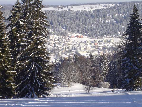 A charming chalet nestled in the snow-covered landscape of Tramelan, Bernese Jura, Switzerland. The vibe of a bustling winter sports scene, including a ski resort, is palpable.