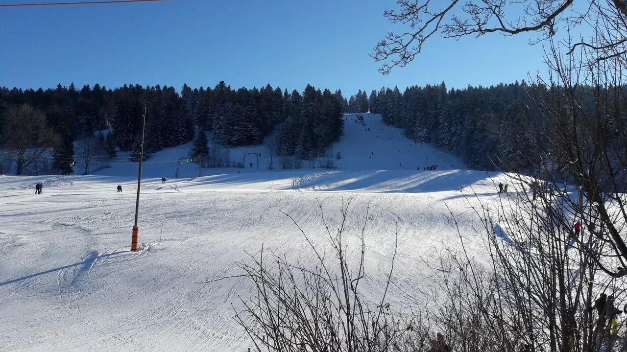 Winter sports lovers enjoying activities at the Tramelan ski resort in Switzerland, surrounded by pristine snow and charming chalets.