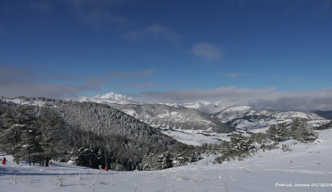 Winter scene at Camurac ski resort in Ariège, France. A charming challet is seen against the backdrop of a snow-coated mountain, offering a picturesque view of the winter sports taking place.