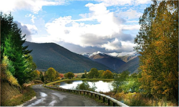 Charming chalet nestled in the beautiful winter scenery of Camurac, France. The mountains in the background and a serene lake add to the tranquil, snowy landscape.