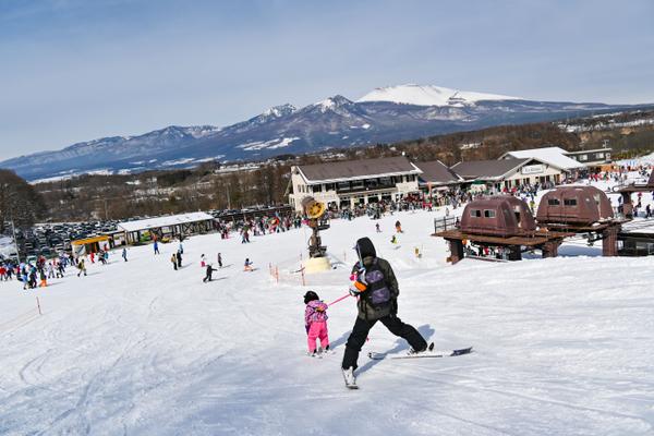 Winter sports scene at Saku Ski Garden Parada in Nagano, Japan, featuring a ski resort, a winter sports centre, and a chalet with skier on the slopes.