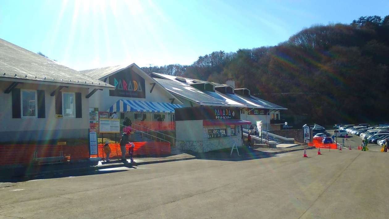 Saku Ski Garden Parada in Japan: a parking with cars parked in front of a building.