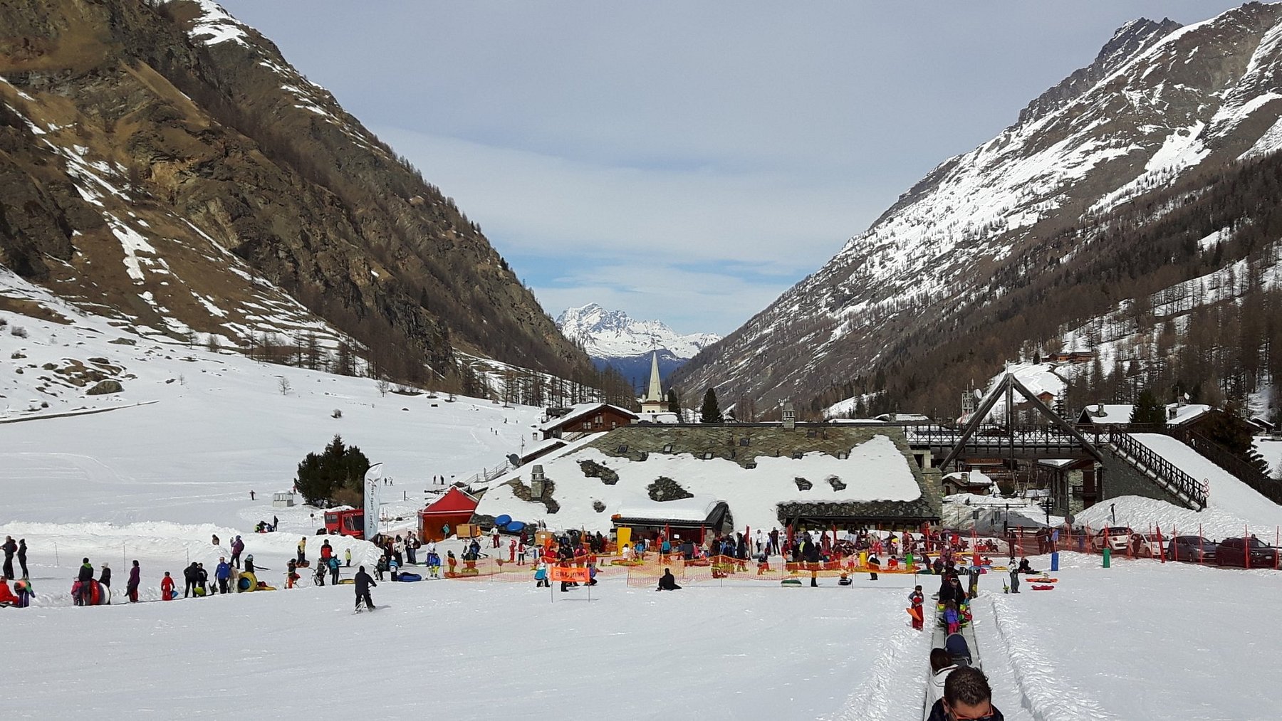 View of the picturesque Rhêmes-Notre-Dame ski resort in Italy featuring a charming chalet, part of the winter sports center, amidst beautiful snow-covered slopes.