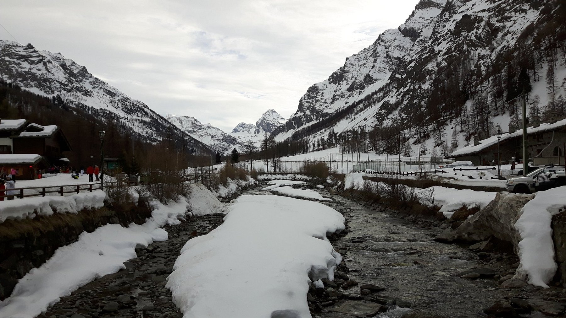 Image displaying a stunning winter scene at Rhêmes-Notre-Dame ski resort in Gran Paradiso, Italy. Includes a challet amid tranquil, snow-laden scenery with a mountain in the backdrop.