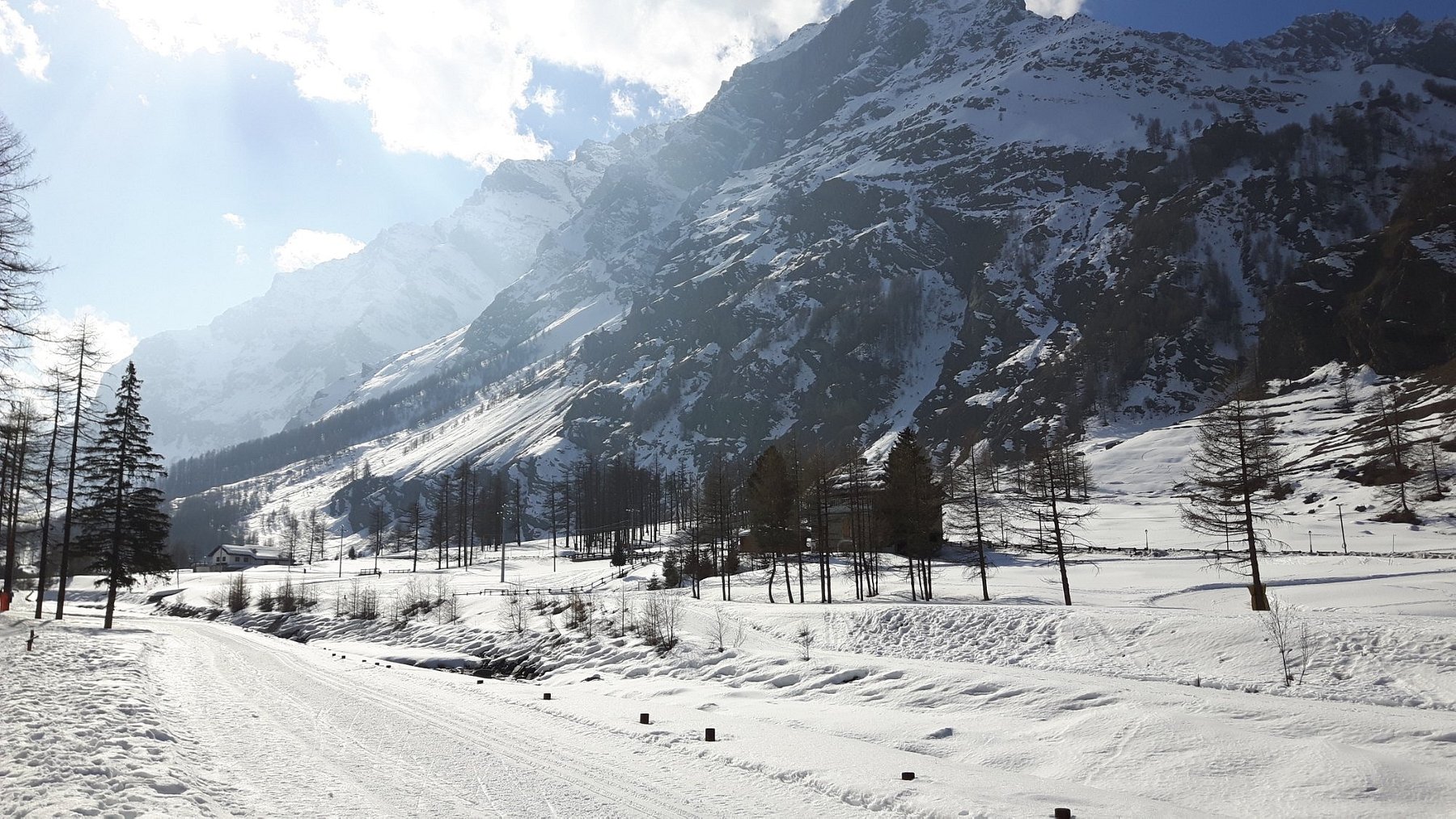 Stunning winter scenery at Comprensorio sciistico Rhêmes-Notre-Dame in Italy, with a chalet nestled in the snow-covered landscape and winter sports enthusiasts enjoying the slopes.
