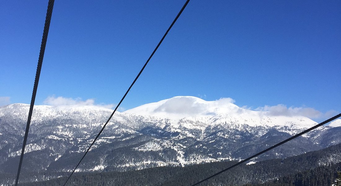 A beautiful winter scene at Yıldıztepe in Kıssenir Turkey featuring a ski lift traversing a snowy mountain located within a bustling ski resort.