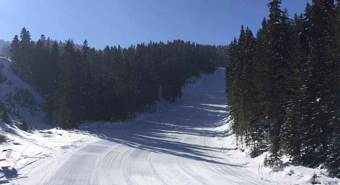 Winter sports scene at Yıldıztepe, Kıssenir, in Central Anatolia, Turkey, featuring a ski resort with a ski lift and a skier, nestled among snowy peaks, and a charming challet nearby.